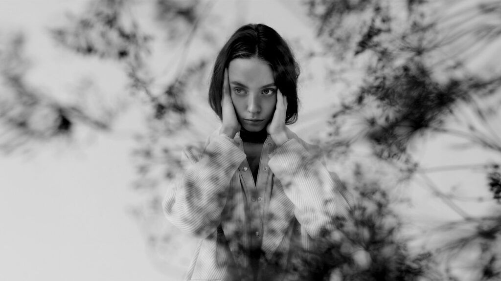 black and white photo of a young woman holding her temples